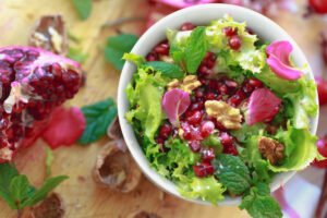 Curly endive salad with pomegranate, nuts, rose petals, peppermint, olive oil, balsamic vinegar, and salt